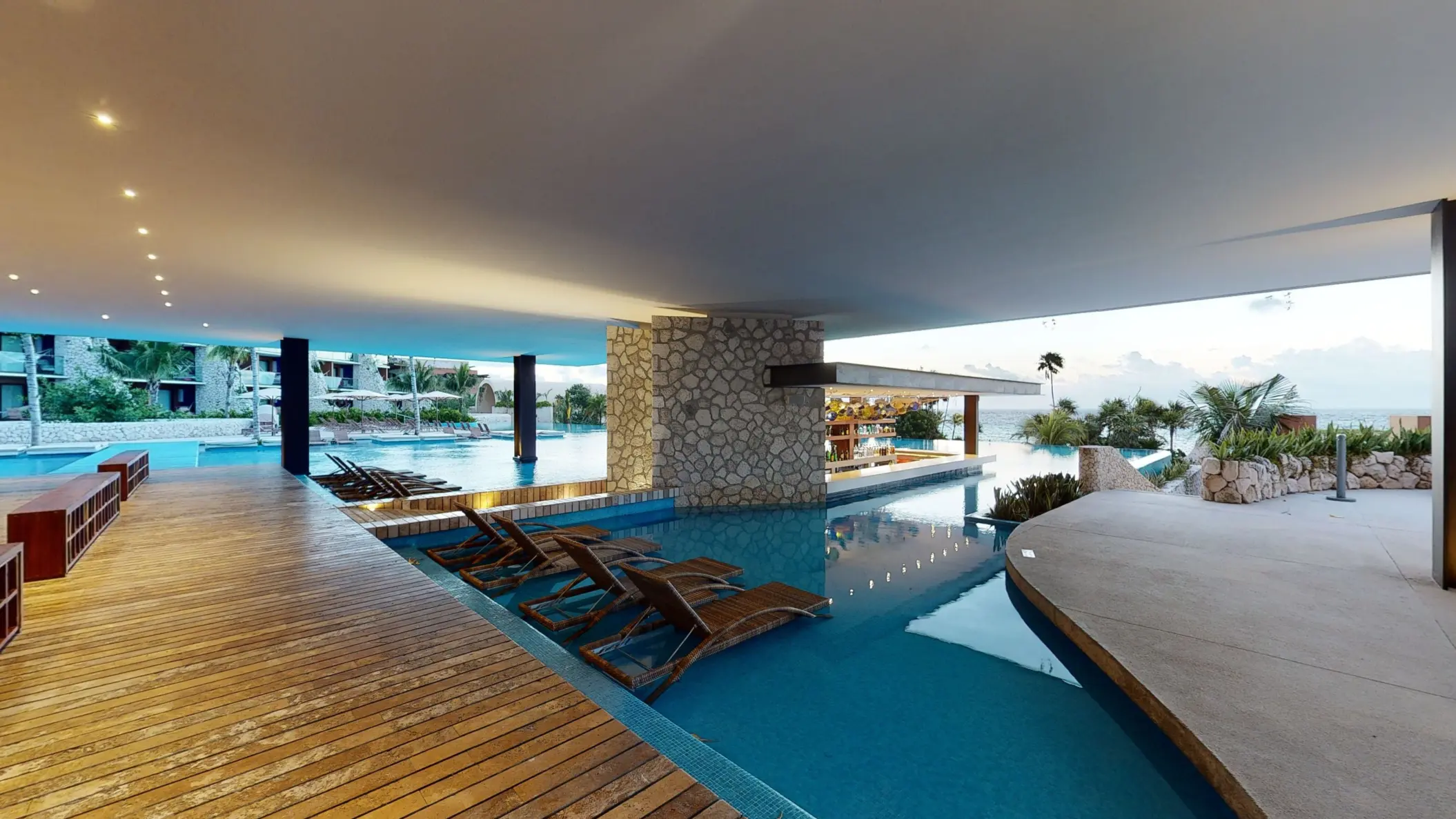 Covered swim-up bar and shaded lounge area with ocean views at Hotel Xcaret Arte.