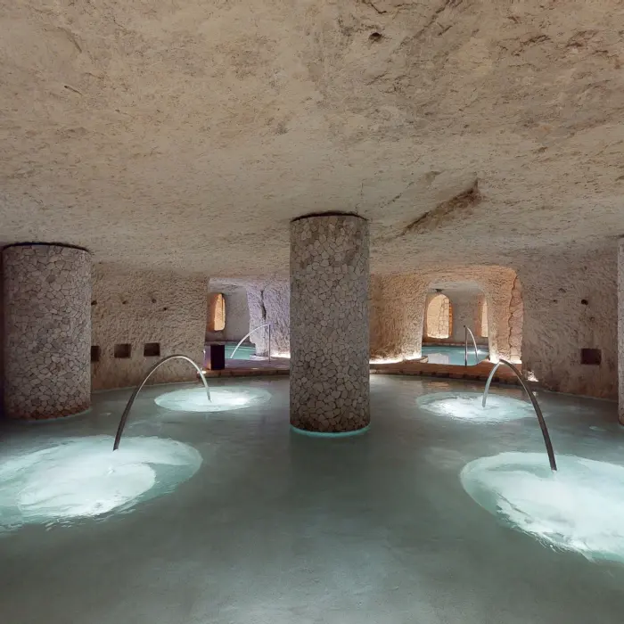 Underground circular hydrotherapy pool with stone columns and relaxing jets at Hotel Xcaret Arte.