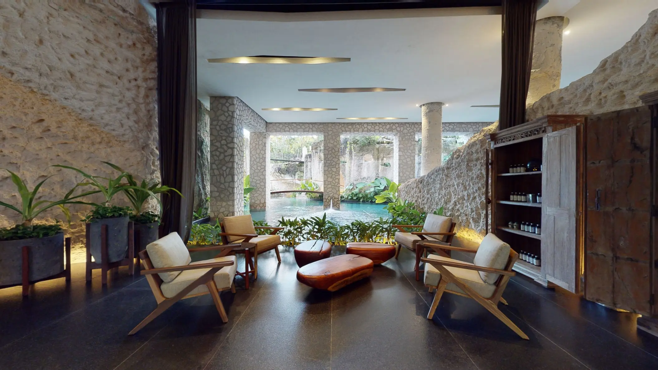 Lounge area at Muluk Spa featuring armchairs and stone walls overlooking the indoor lagoon pool.