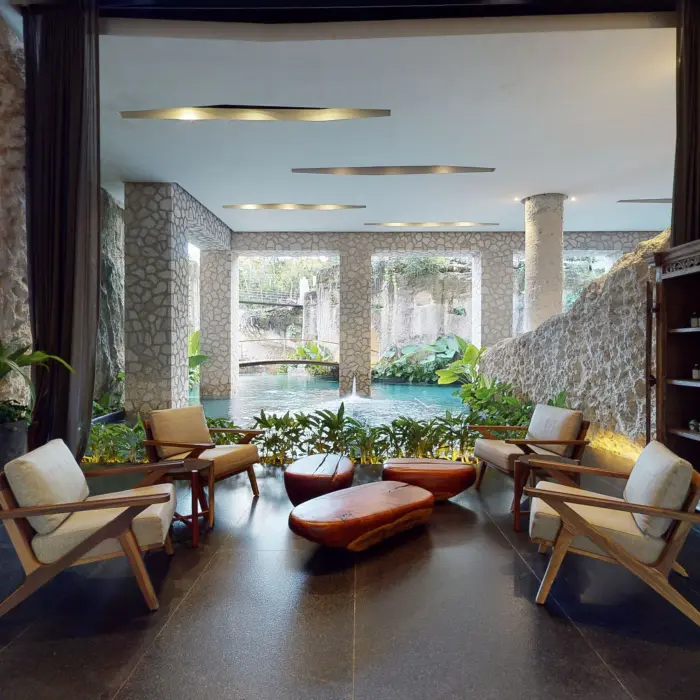 Lounge area at Muluk Spa featuring armchairs and stone walls overlooking the indoor lagoon pool.