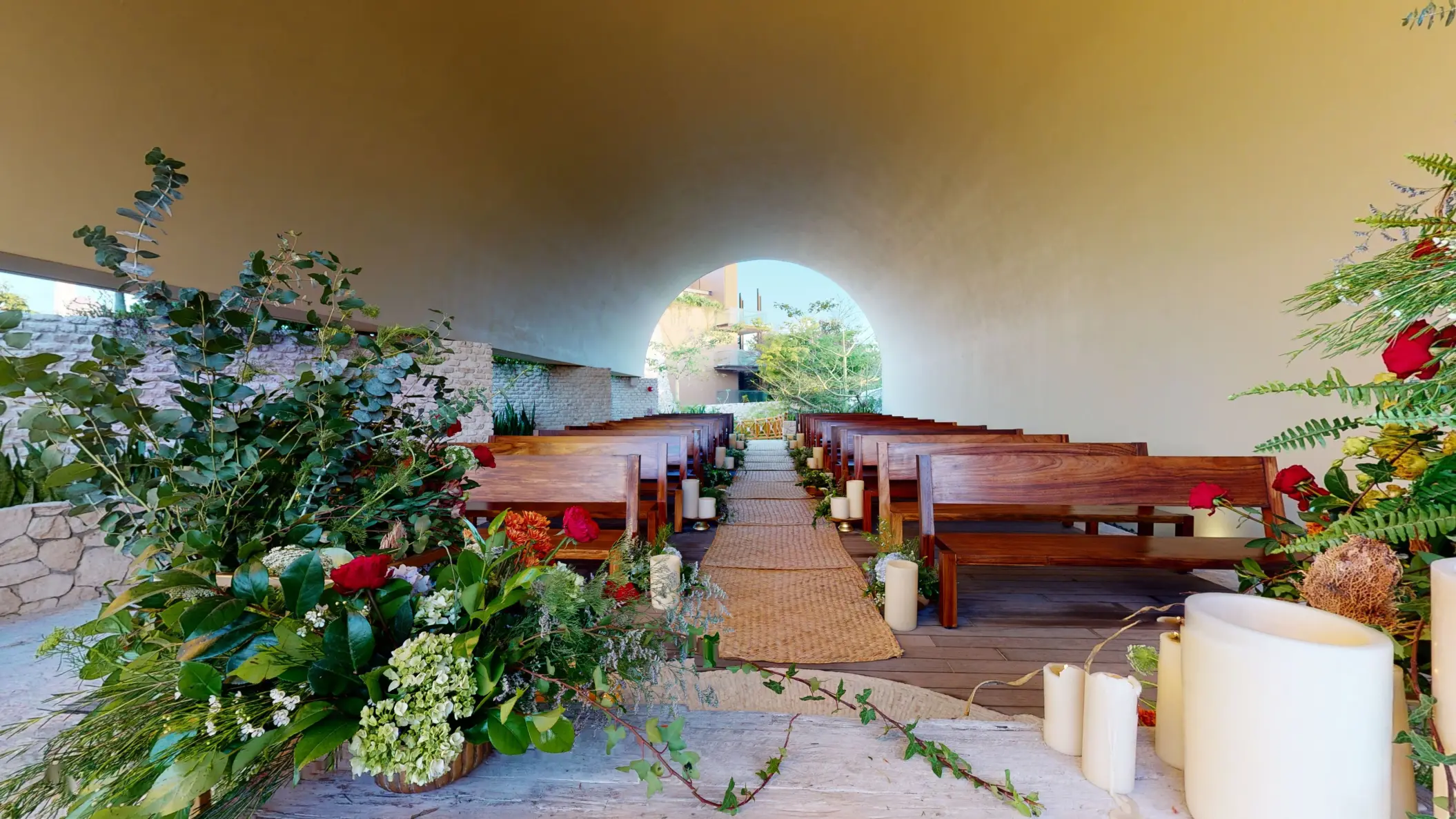 Indoor wedding chapel with arched ceiling, floral aisle décor, and wooden pews at Hotel Xcaret Arte.