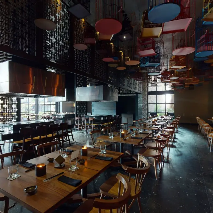 Tah Xido restaurant with open teppanyaki stations, moody lighting, and colorful hanging decor overhead.