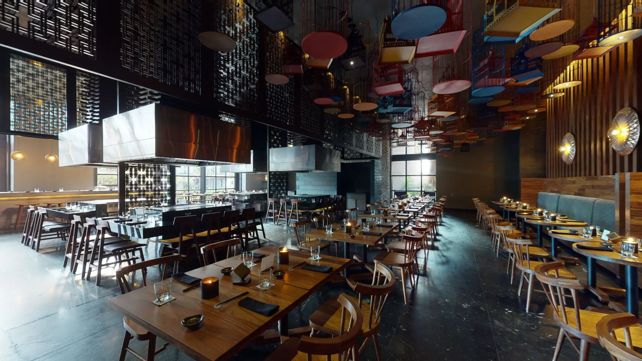 Tah Xido restaurant with open teppanyaki stations, moody lighting, and colorful hanging decor overhead.