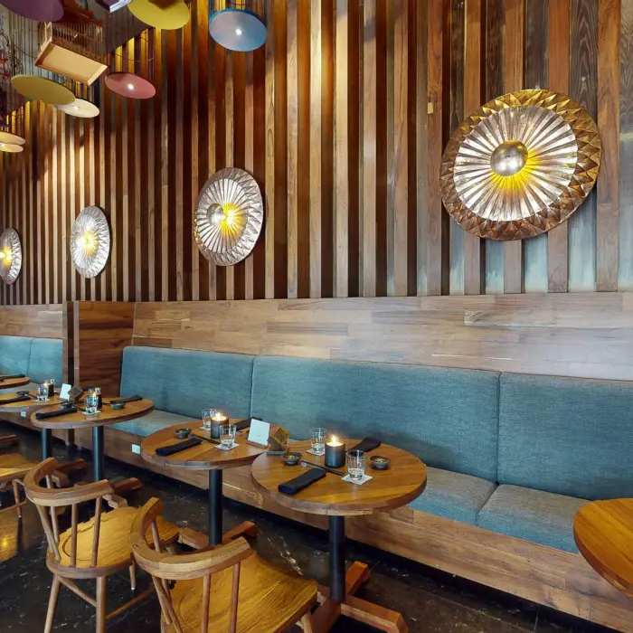 Tah Xido restaurant seating with wood-paneled walls, teal booth seating, and round wooden tables.