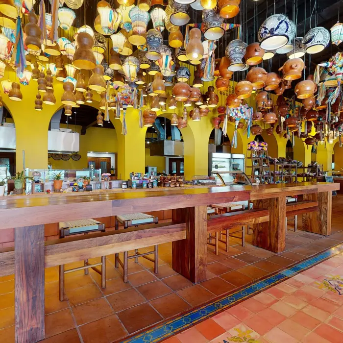 Lively buffet restaurant with vibrant yellow arches, wood accents, and hanging artisan pottery decor.