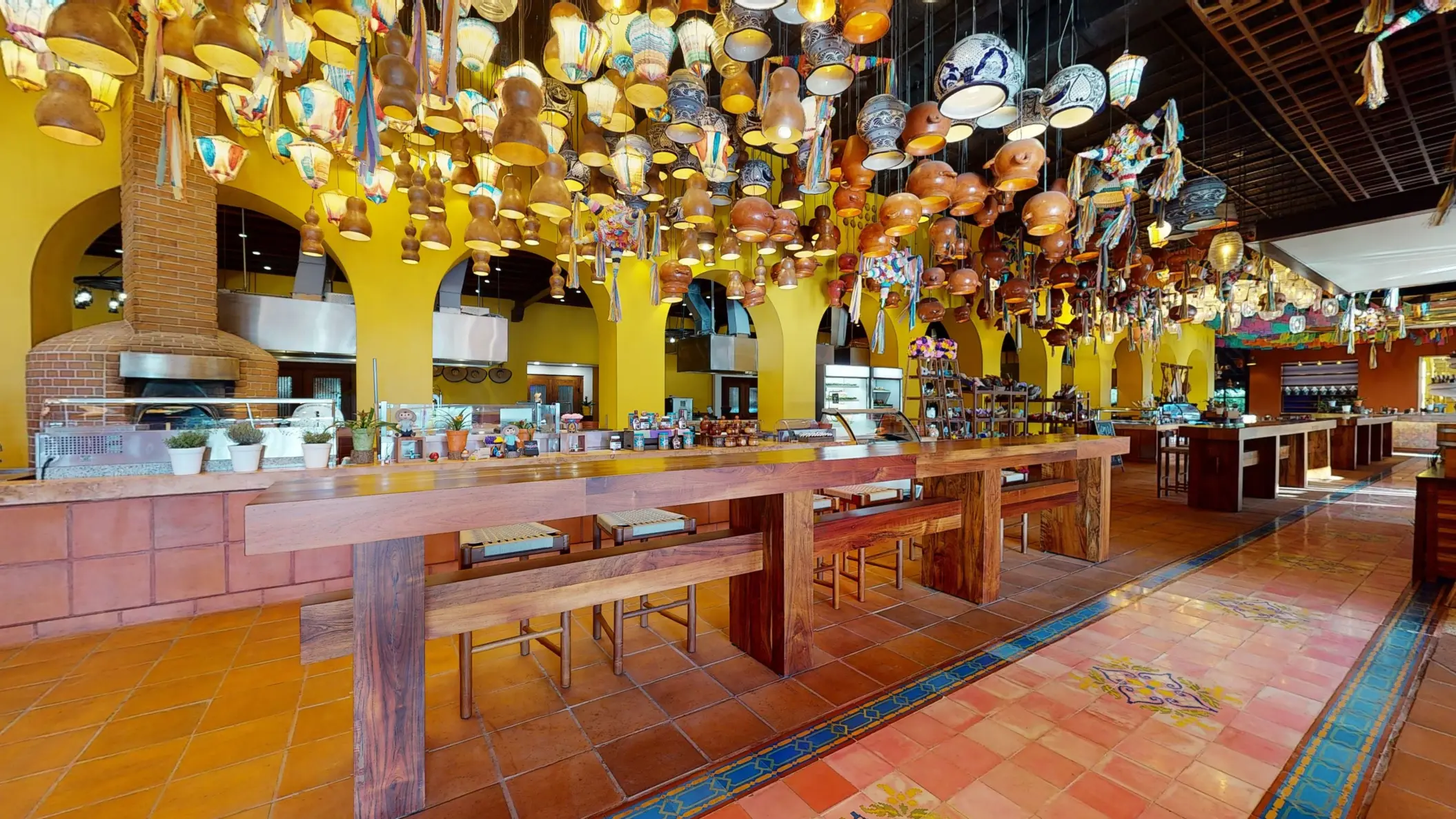 Lively buffet restaurant with vibrant yellow arches, wood accents, and hanging artisan pottery decor.