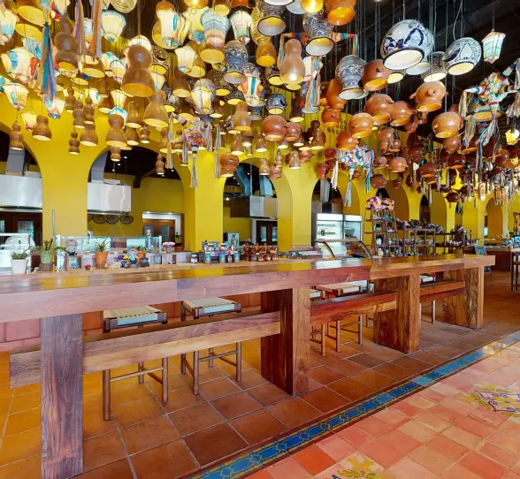 Lively buffet restaurant with vibrant yellow arches, wood accents, and hanging artisan pottery decor.