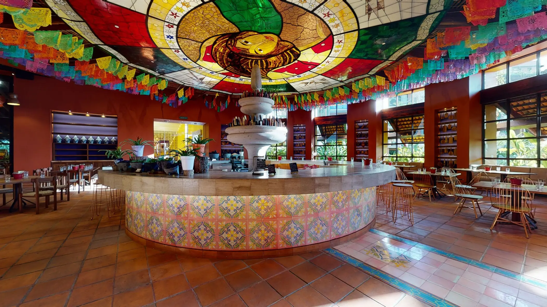 Mercado de San Juan restaurant with mosaic tile design, fountain centerpiece, and stained glass ceiling with papel picado.