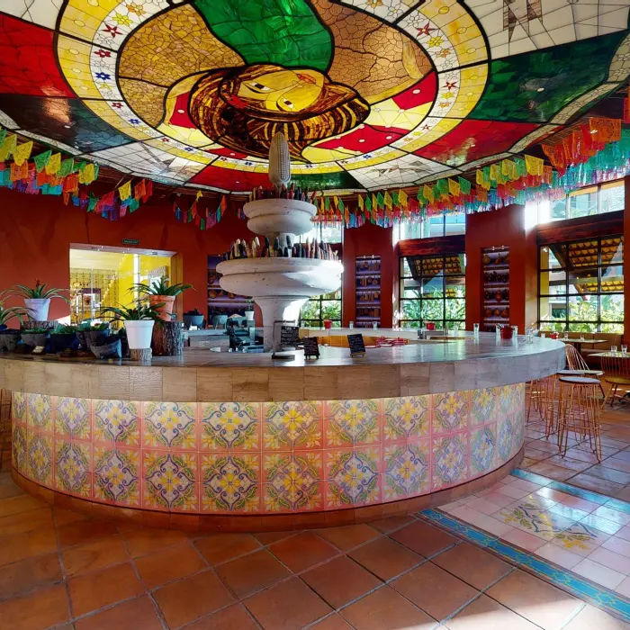 Mercado de San Juan restaurant with mosaic tile design, fountain centerpiece, and stained glass ceiling with papel picado.