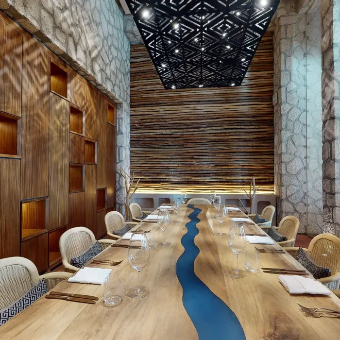 Private dining room with a live-edge wood table, artistic lighting, and natural textures all around.