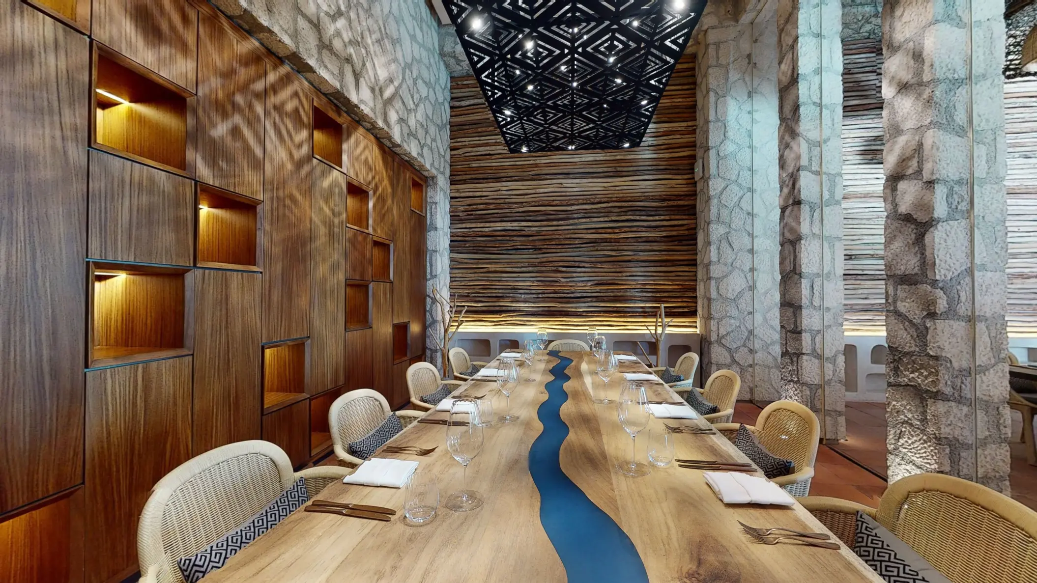 Private dining room with a live-edge wood table, artistic lighting, and natural textures all around.