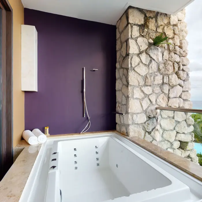 Private outdoor hot tub with ocean views, stone wall, and a deep purple accent wall for extra style.
