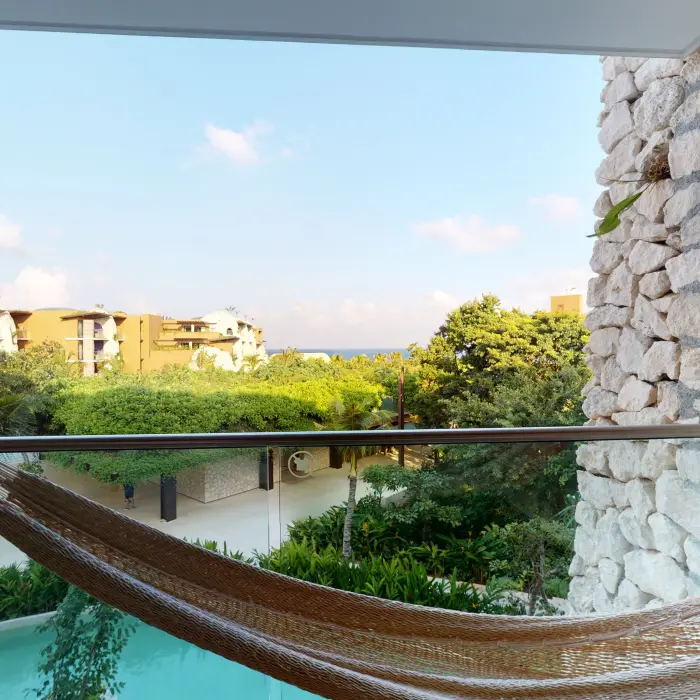 Private hammock with garden and partial ocean view from the balcony of Hotel Xcaret Arte suite.
