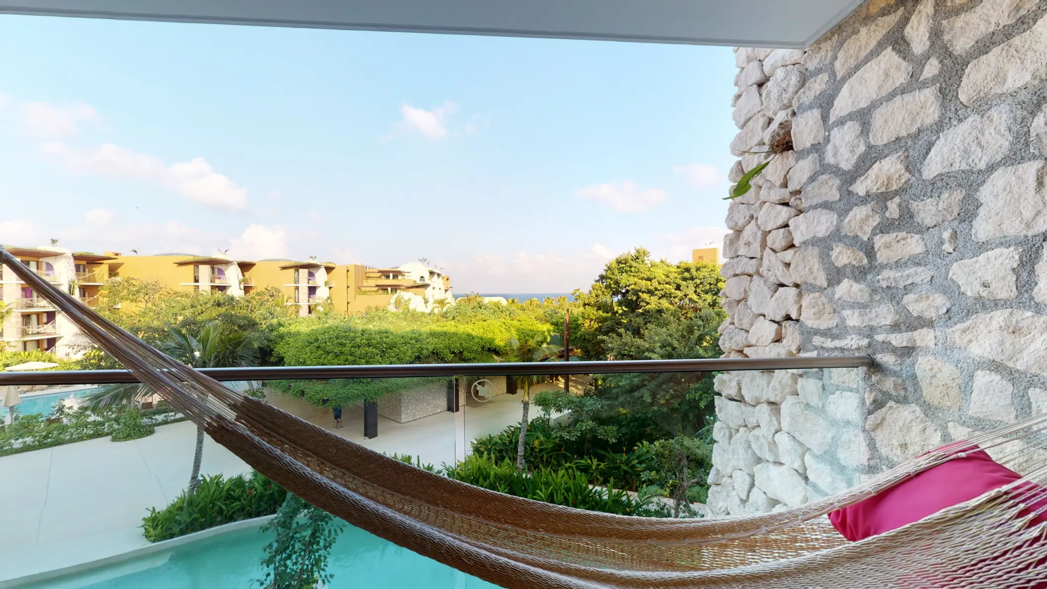 Private hammock with garden and partial ocean view from the balcony of Hotel Xcaret Arte suite.