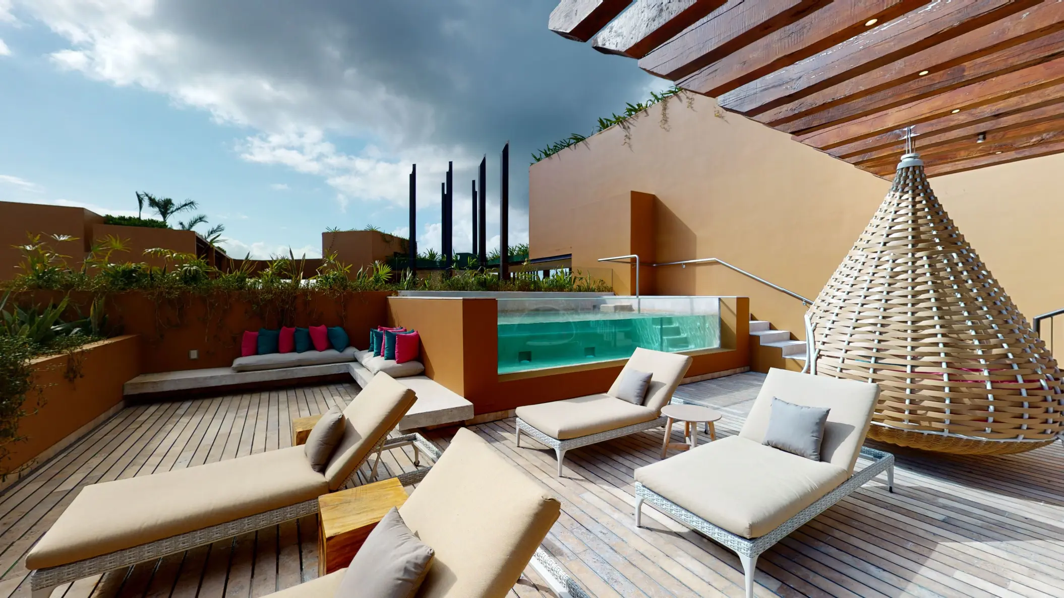 Secluded sun deck with loungers, plunge pool, and woven cabana seating at Hotel Xcaret Arte.