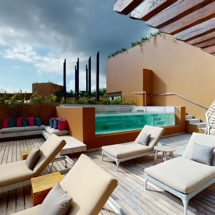 Secluded sun deck with loungers, plunge pool, and woven cabana seating at Hotel Xcaret Arte.