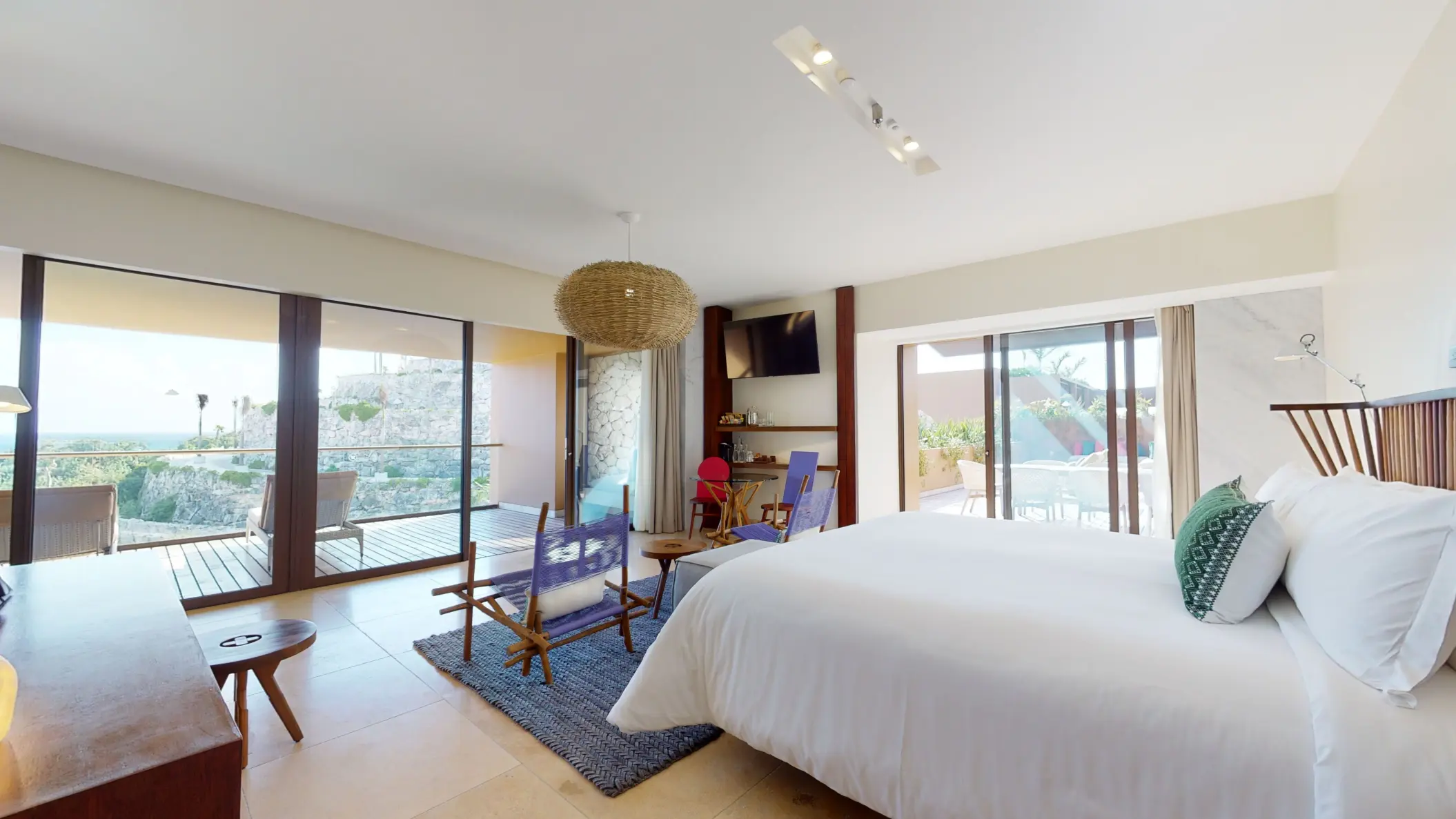 Spacious guest room with modern decor, large windows, and dual terraces overlooking nature and rooftop.