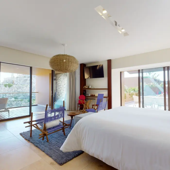 Spacious guest room with modern decor, large windows, and dual terraces overlooking nature and rooftop.