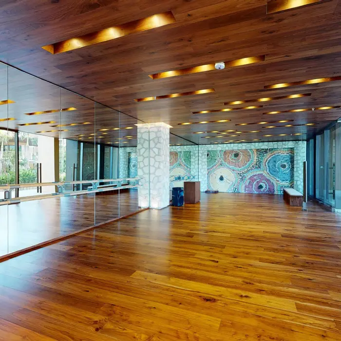 Bright dance or yoga studio with mirrored wall, hardwood floors, and mosaic art under modern ceiling lights.
