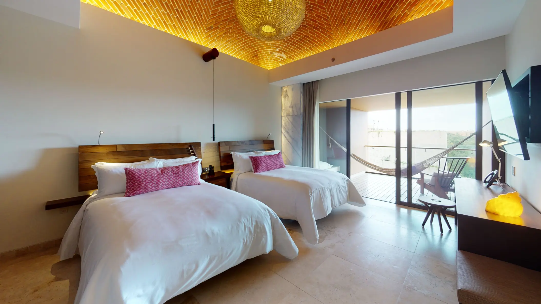 Spacious modern guest room with two queen beds, vaulted brick ceiling, and balcony hammock.
