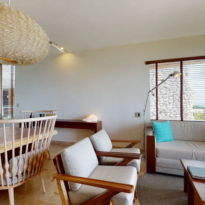 Open-concept living and dining room with ocean view, wooden furniture, and coastal-inspired modern design.