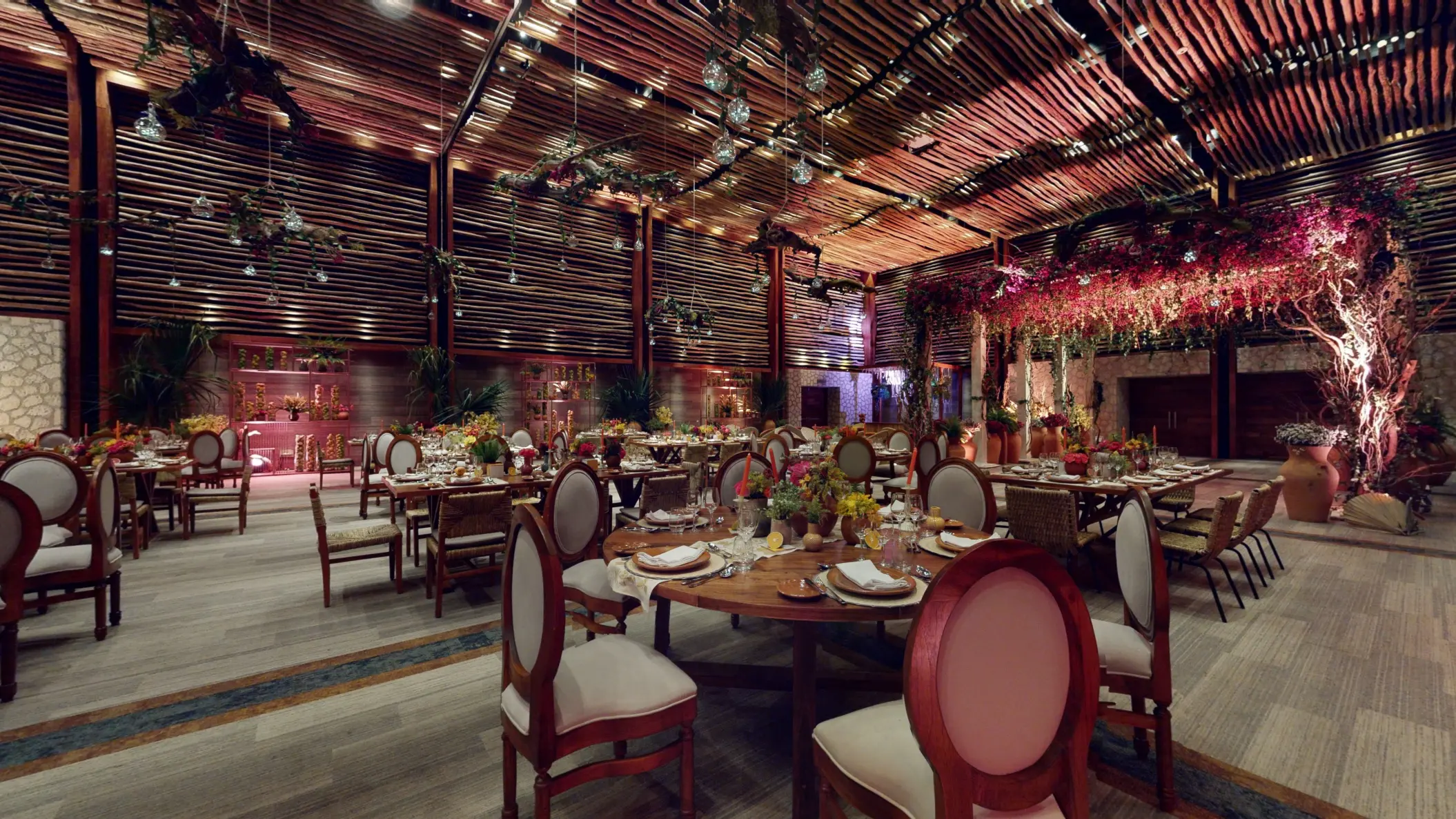 Lavish indoor wedding venue decorated with colorful florals and rustic wood design.