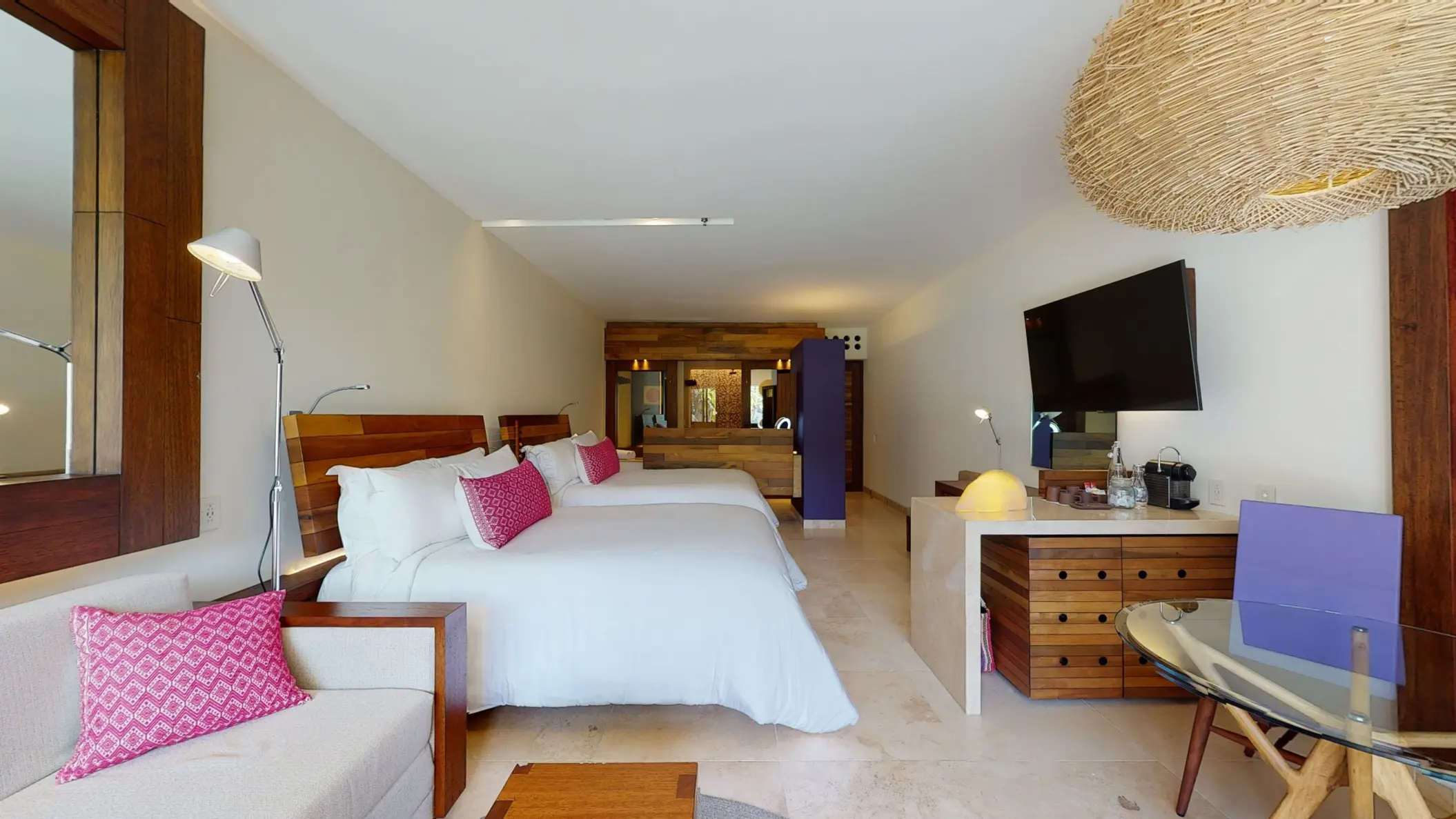 Spacious hotel room with two queen beds, warm lighting, and wood furnishings.