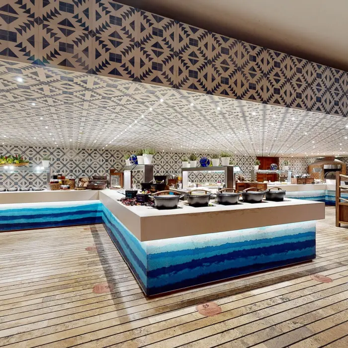 Wide view of Xcaret Arte’s vibrant buffet with geometric tile décor and blue-accented counters.