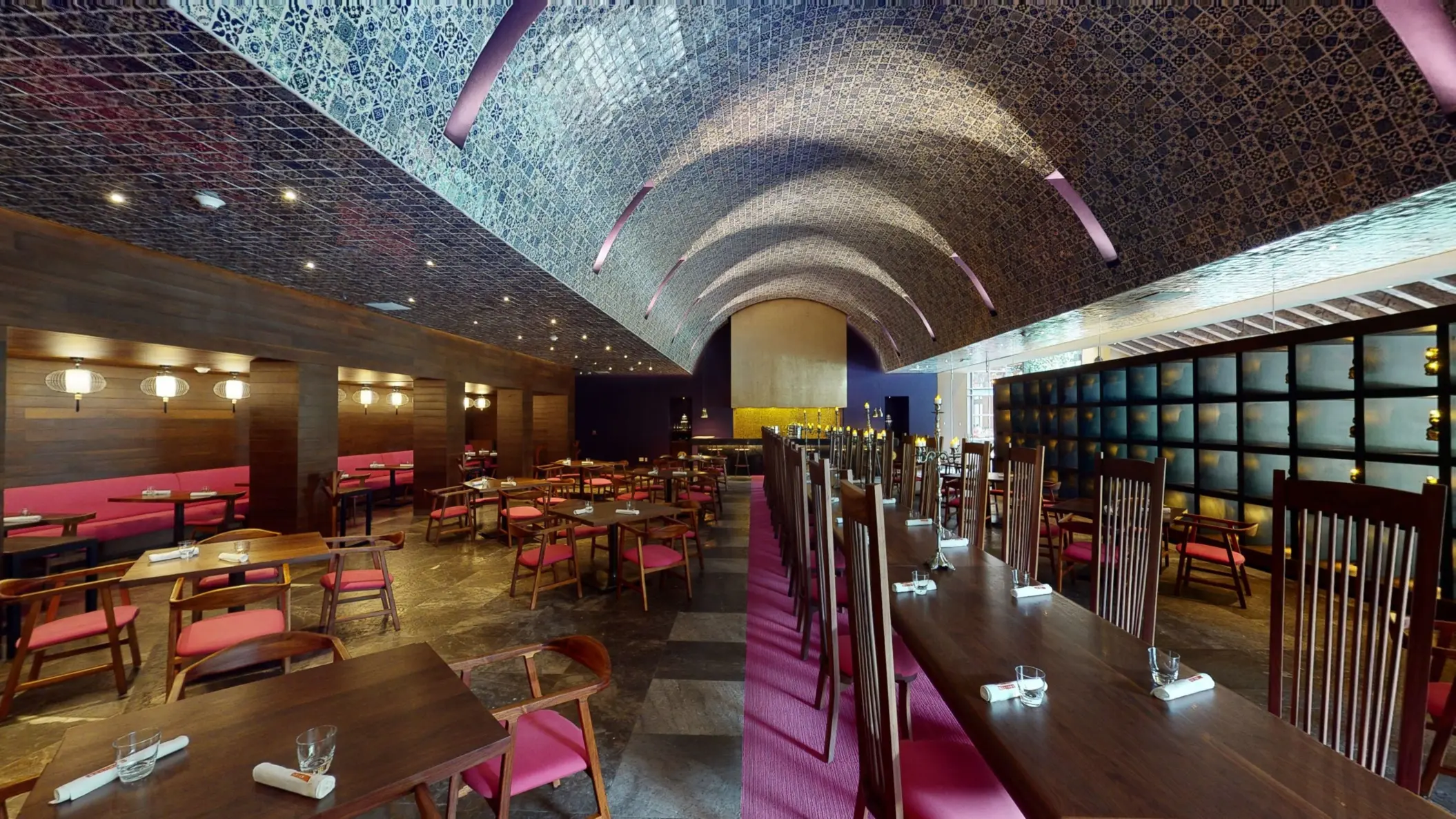 Elegant dining room with arched tiled ceiling, pink accents, and dark wood furnishings at Hotel Xcaret Arte restaurant.