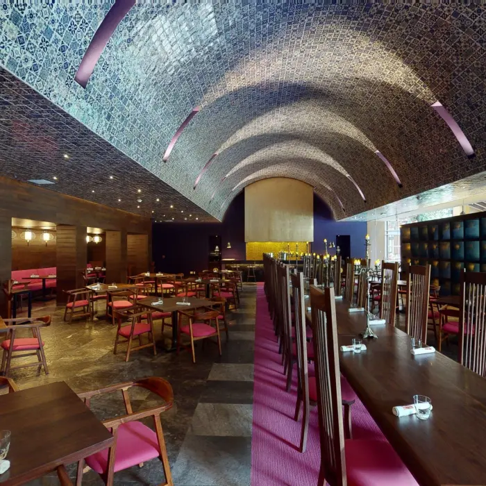 Elegant dining room with arched tiled ceiling, pink accents, and dark wood furnishings at Hotel Xcaret Arte restaurant.
