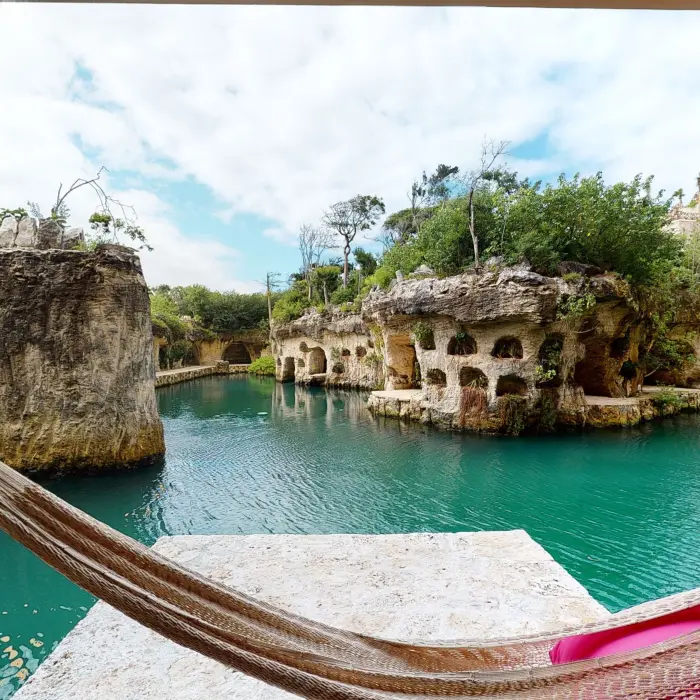 Hammock hanging over turquoise river view with natural rock formations and lush jungle surroundings at Hotel Xcaret Arte.