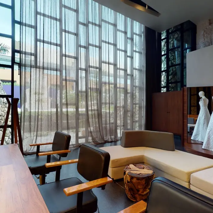 Bridal lounge with wedding dresses on display, makeup stations, and large windows at Hotel Xcaret Arte's beauty salon.