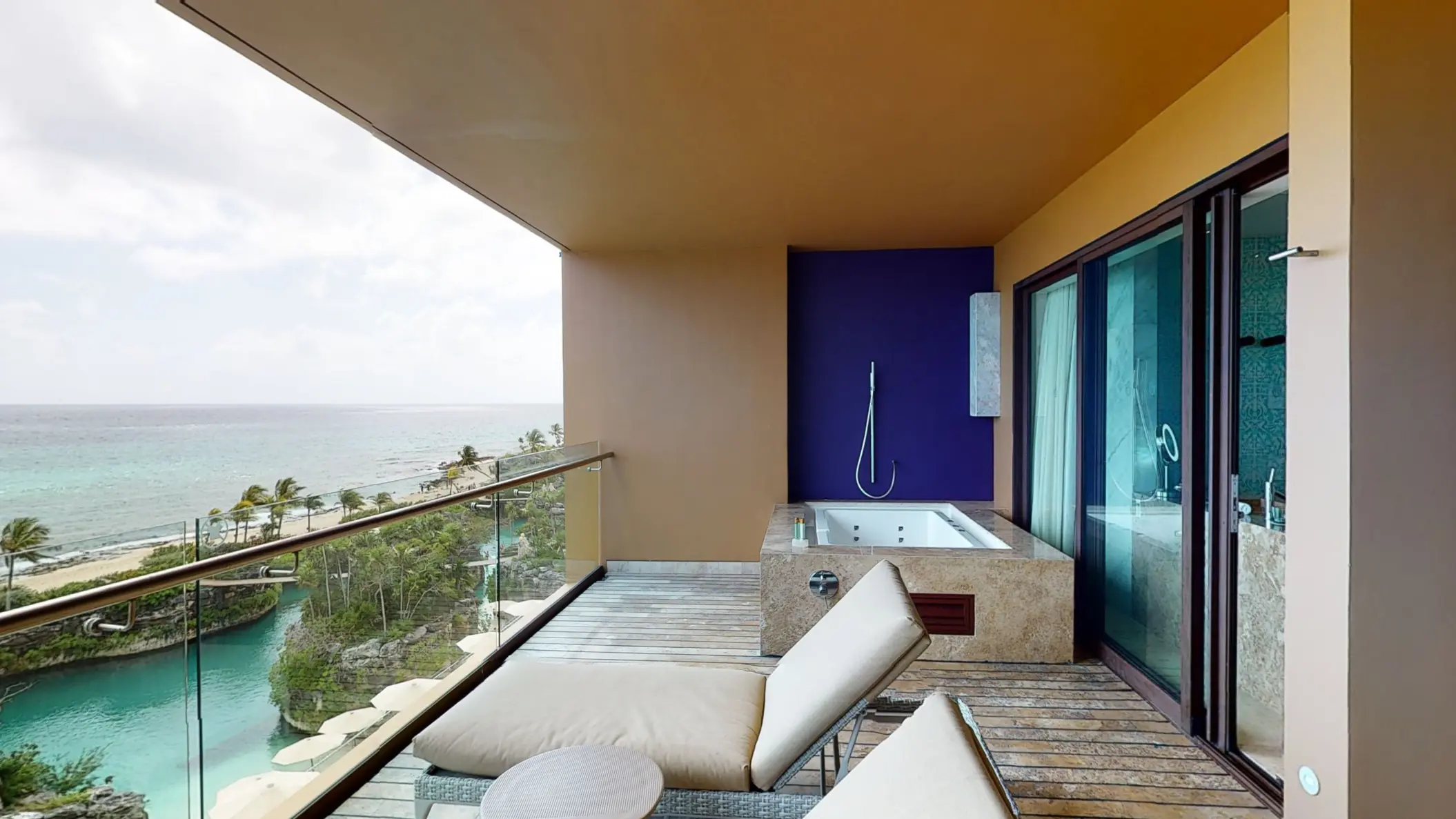 Oceanview balcony with lounge chairs and a private outdoor hot tub at Hotel Xcaret Arte.
