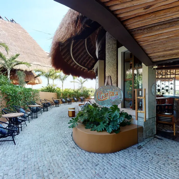 Cantina V.I.A.I.P.Y entrance with outdoor seating area with tropical plants & cobblestone floor.