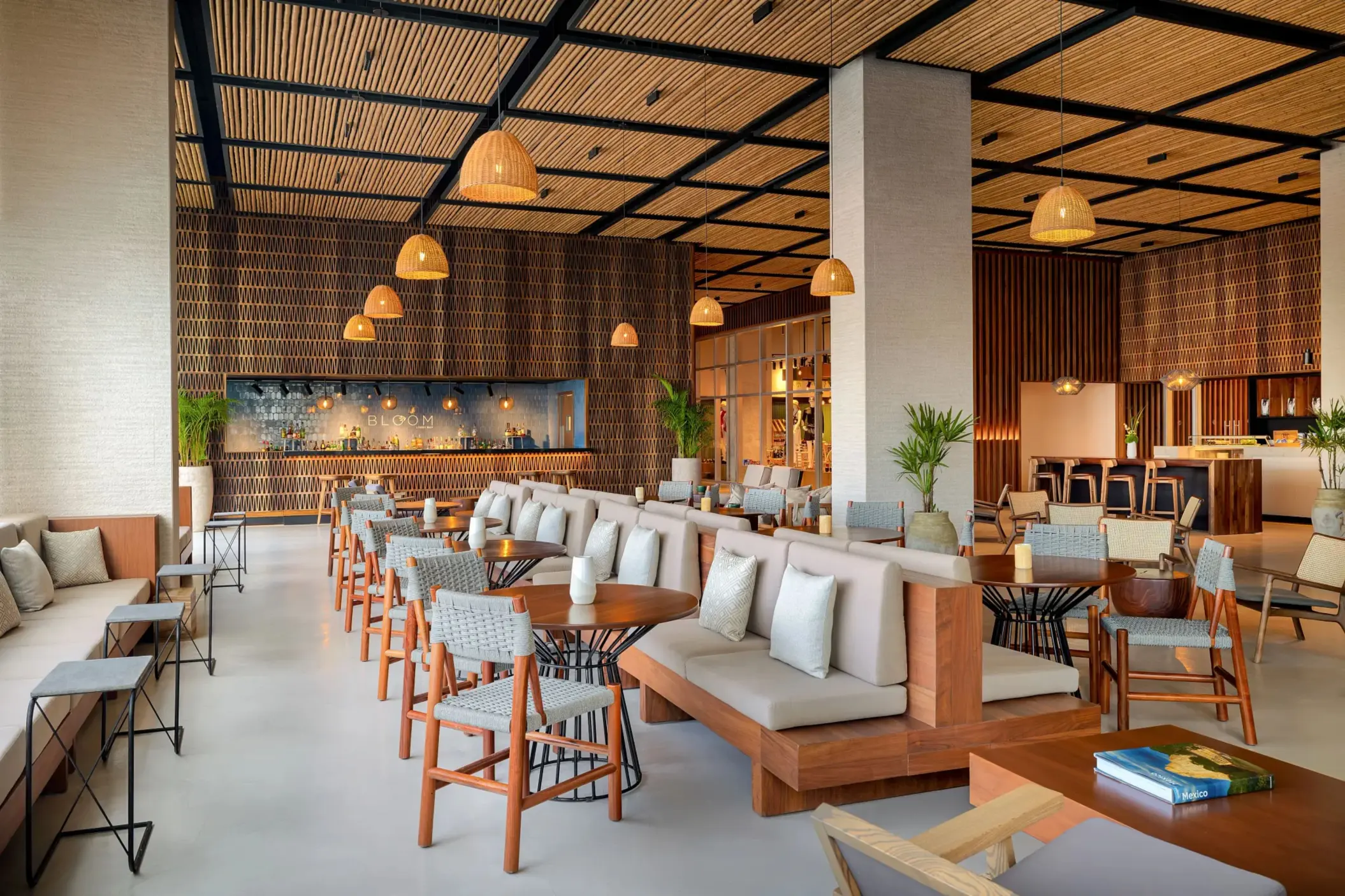 Chic hotel lobby lounge with wooden accents, cozy seating, pendant lights, and Bloom bar in the background.