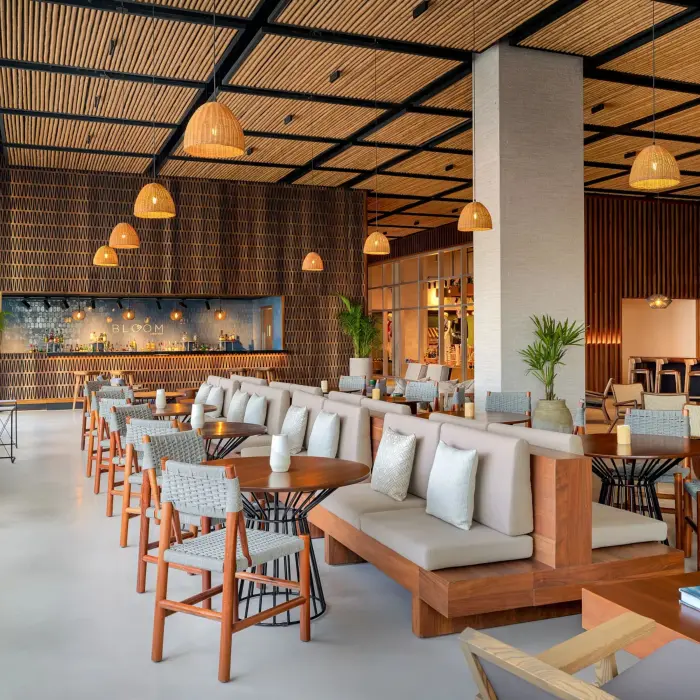 Chic hotel lobby lounge with wooden accents, cozy seating, pendant lights, and Bloom bar in the background.