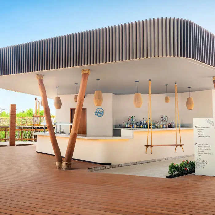 Modern outdoor bar with curved roof, wood accents, swing seating, and bright, airy design elements.