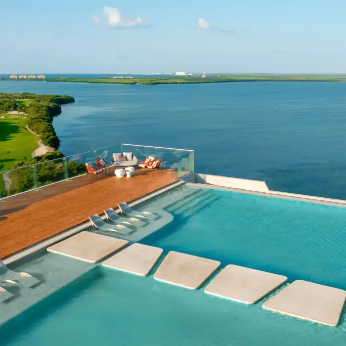 Infinity rooftop pool with sun loungers, panoramic lagoon views, and modern lounge area at the corner.