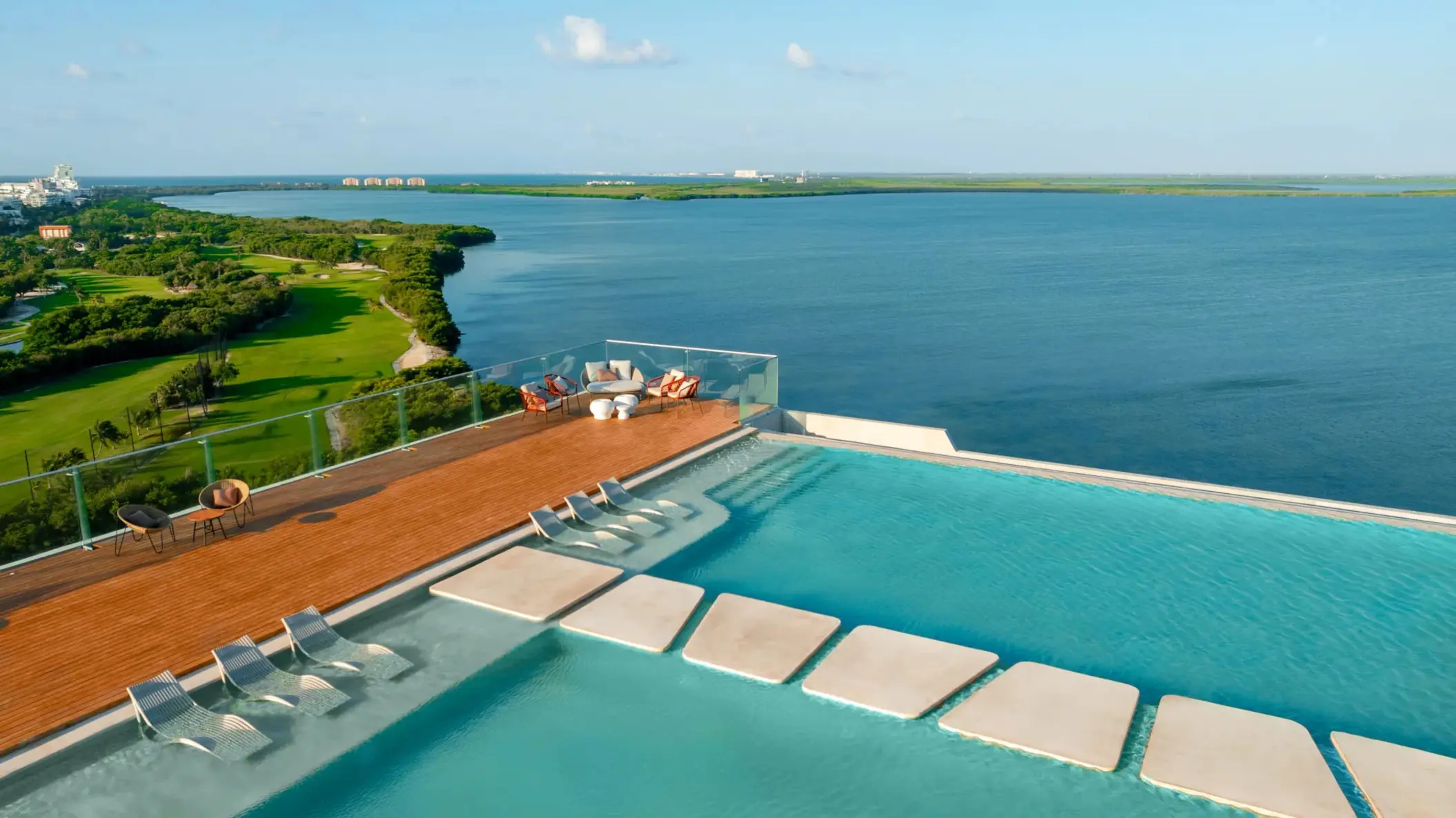 Infinity rooftop pool with sun loungers, panoramic lagoon views, and modern lounge area at the corner.