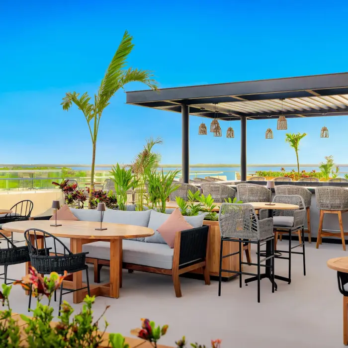 Open-air lounge with wood details, plush seating, and soft lighting surrounded by lush jungle foliage.