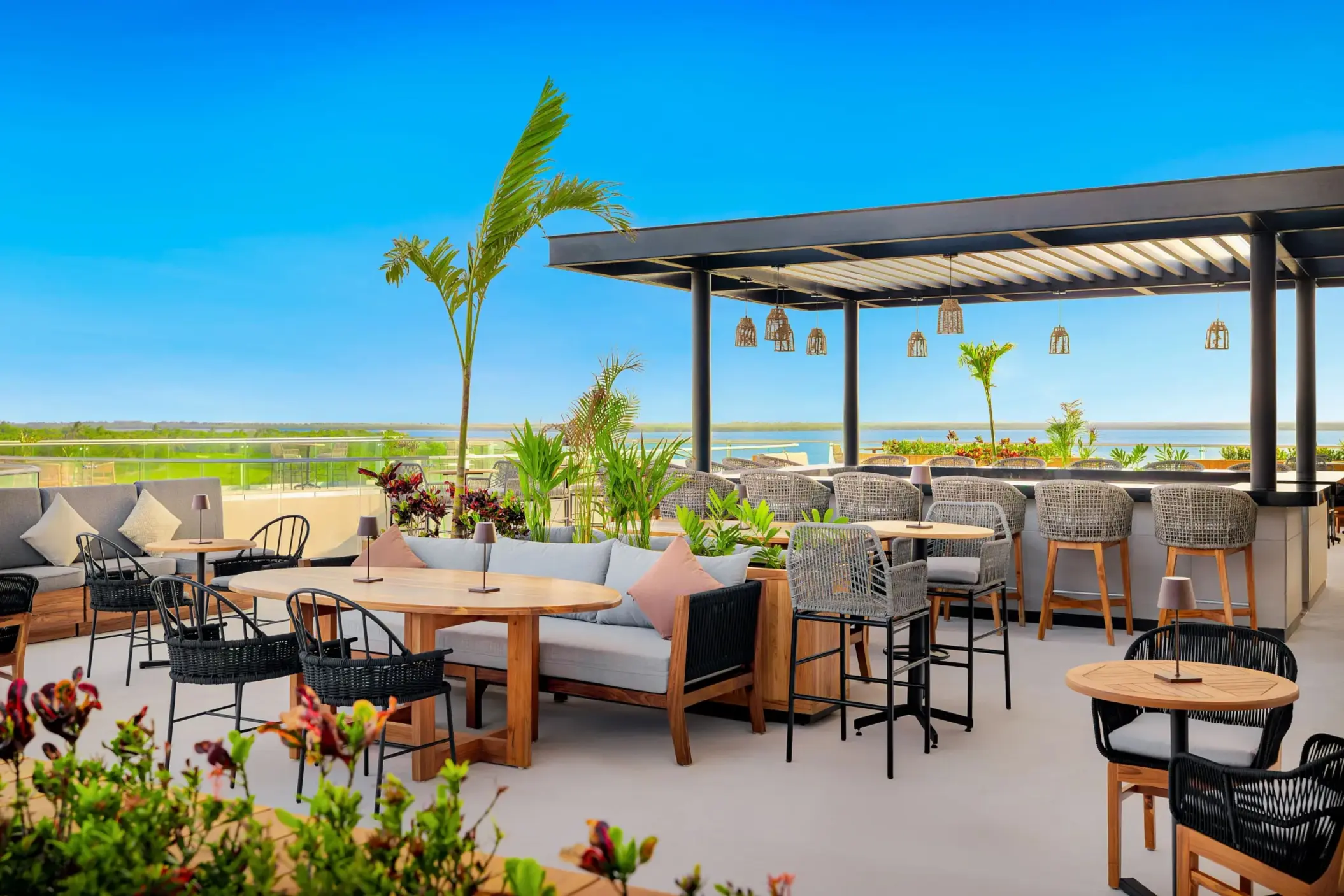 Open-air lounge with wood details, plush seating, and soft lighting surrounded by lush jungle foliage.