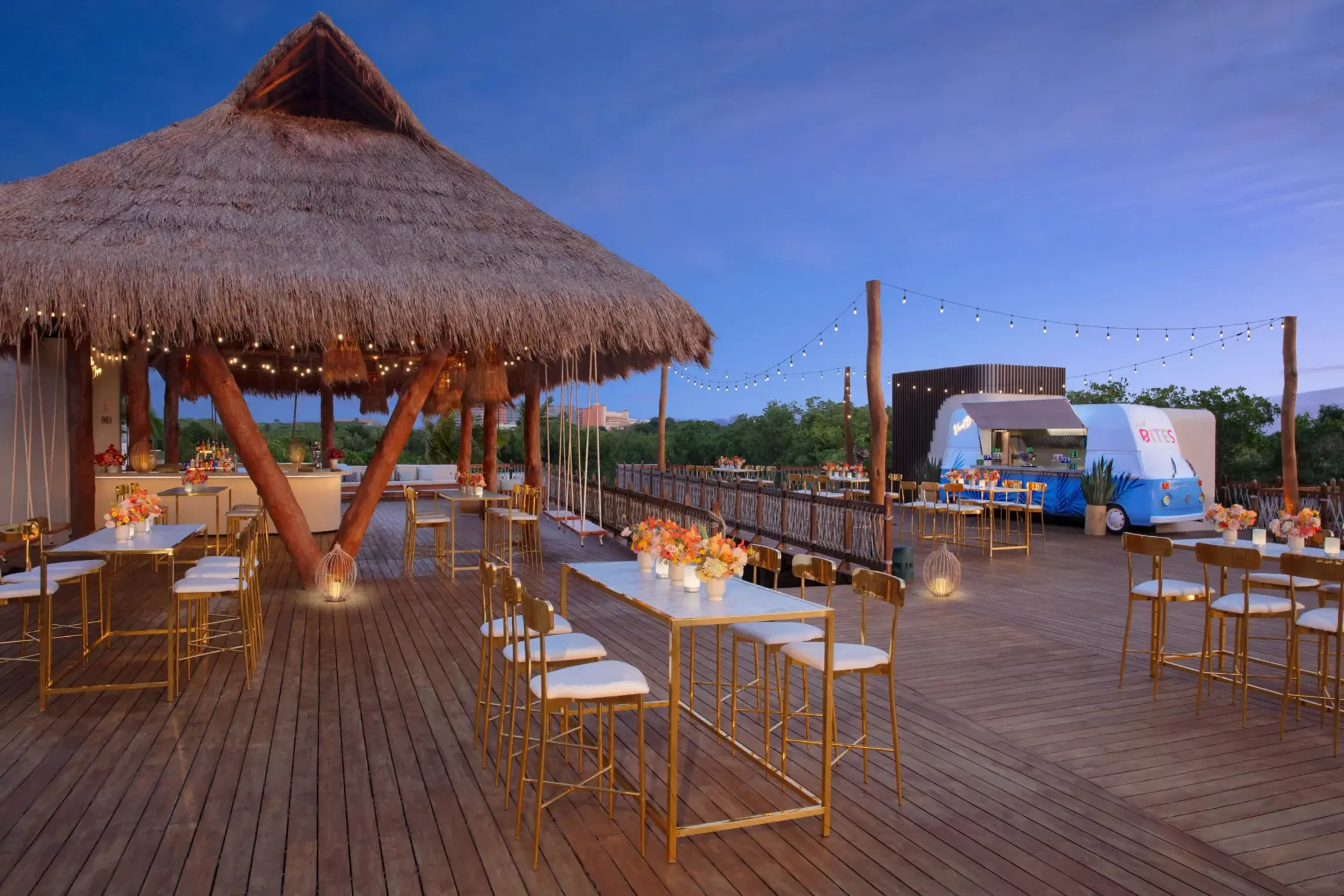 Elegant cocktail event setup on the Amber Deck with round tables, floral décor, and lush jungle backdrop.