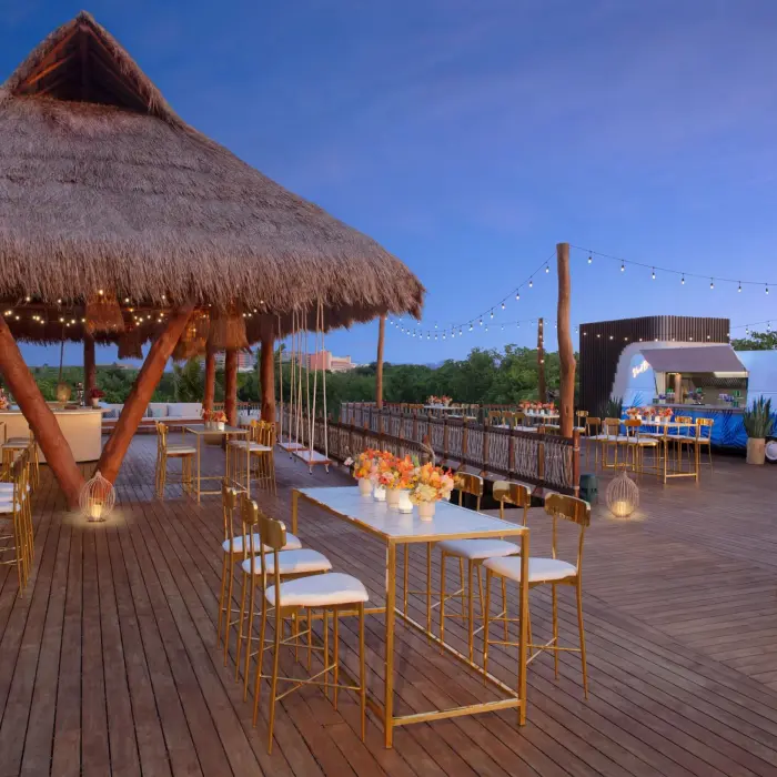 Elegant cocktail event setup on the Amber Deck with round tables, floral décor, and lush jungle backdrop.