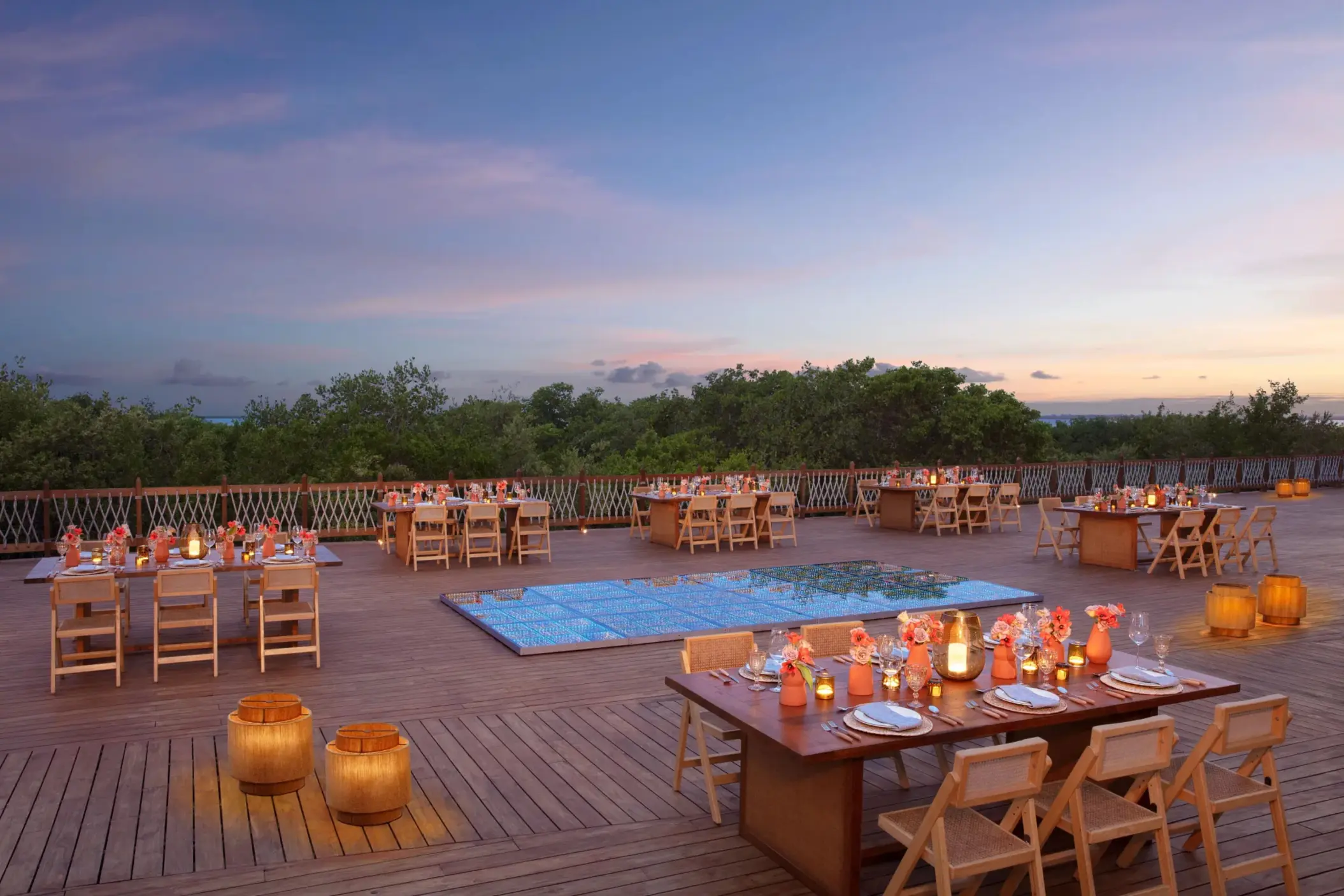 Romantic outdoor gala dinner setup on Amber Deck with candles, string lights, and surrounding palm trees.