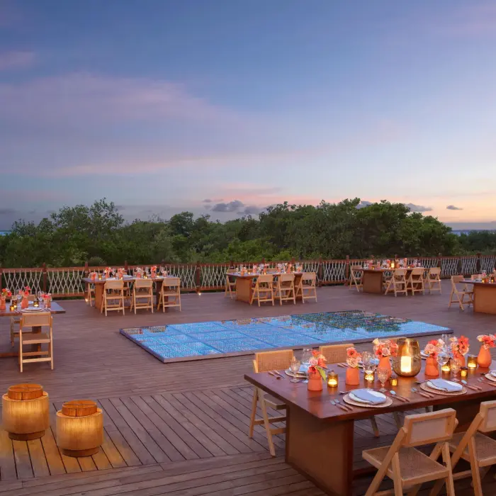 Romantic outdoor gala dinner setup on Amber Deck with candles, string lights, and surrounding palm trees.