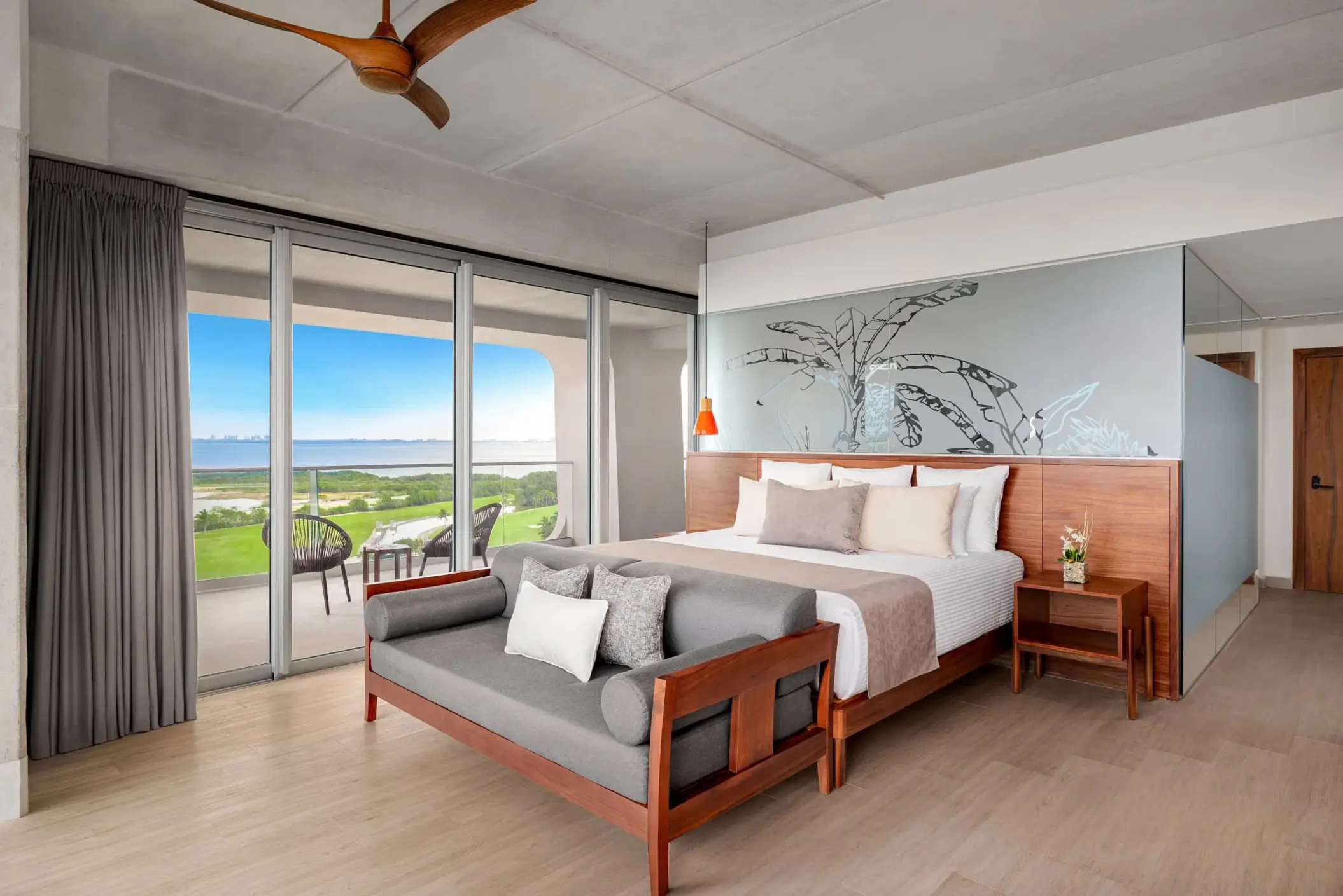 Spacious modern suite with king bed, wooden bench, and balcony overlooking lush greenery in Vantage Club section.