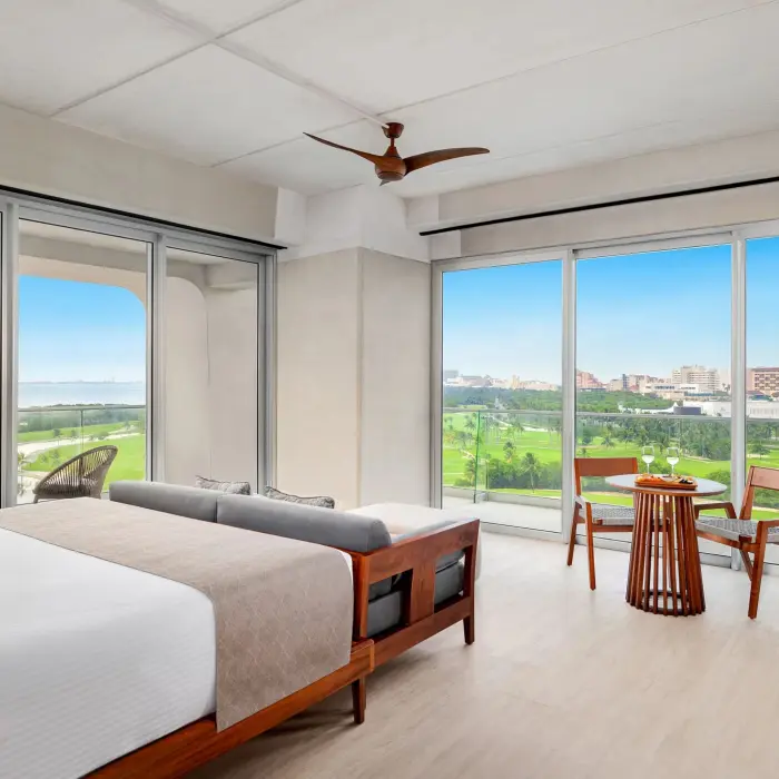 Elegant Vantage Club suite with king bed, warm lighting, and balcony overlooking golf course and jungle.