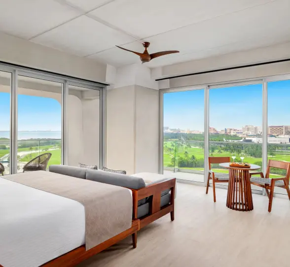 Elegant Vantage Club suite with king bed, warm lighting, and balcony overlooking golf course and jungle.