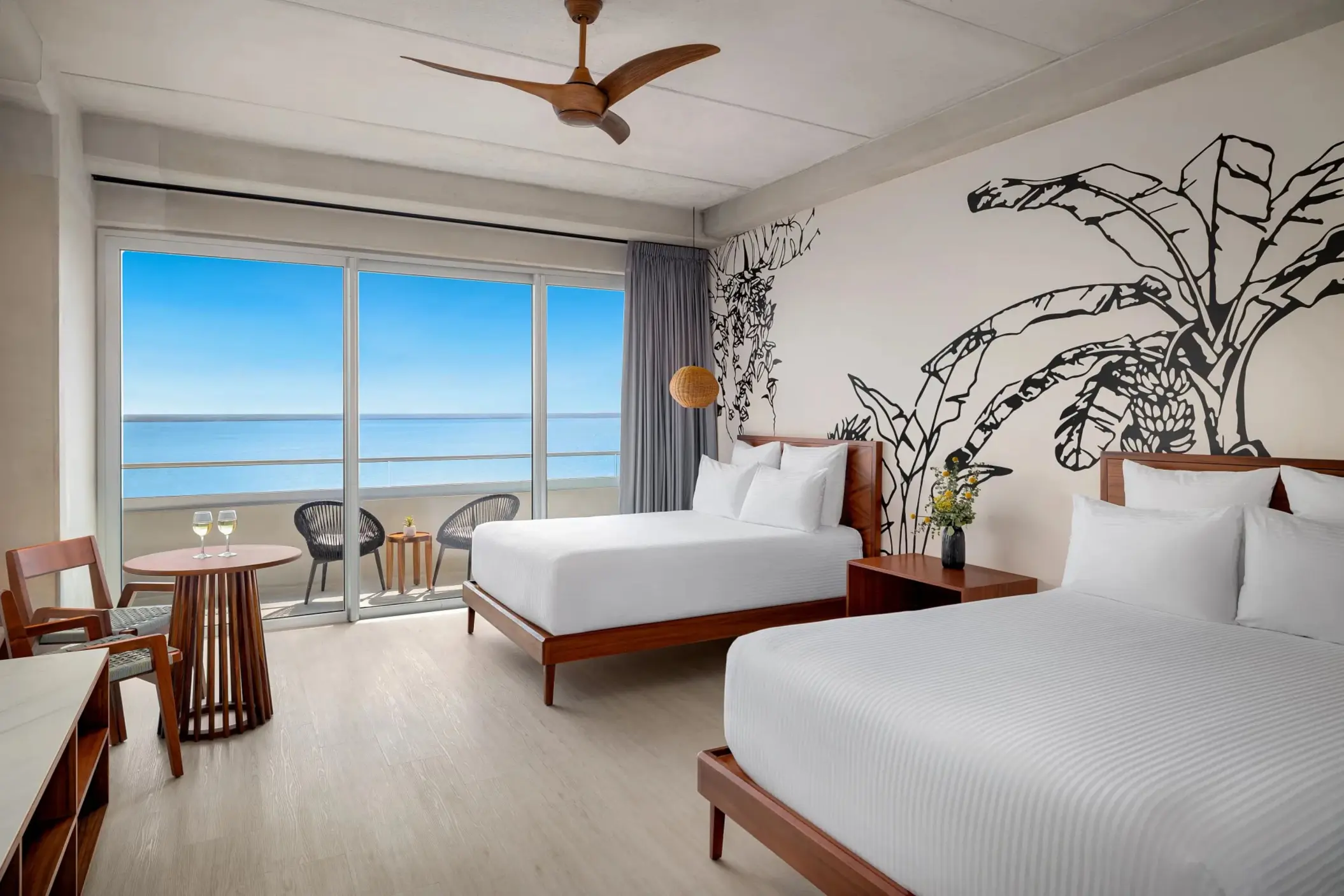 Deluxe double room with two beds, minimalist décor, and private balcony with a tropical garden view.