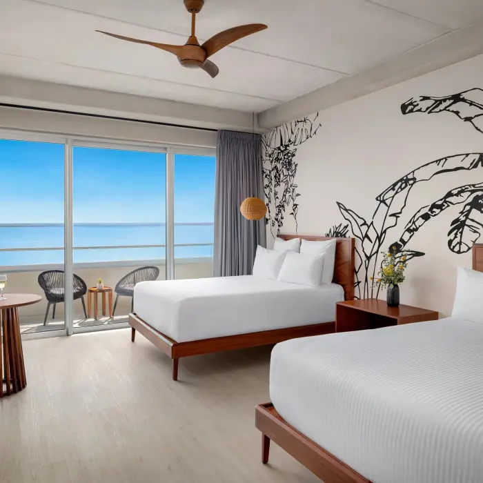 Deluxe double room with two beds, minimalist décor, and private balcony with a tropical garden view.